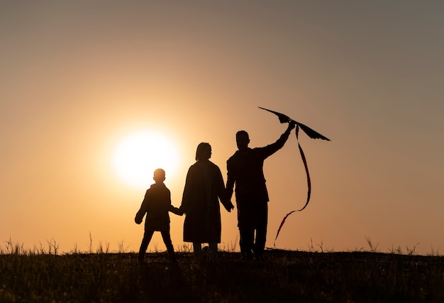 Vollbild-Familiensilhouette, die Spaß bei Sonnenuntergang hat
