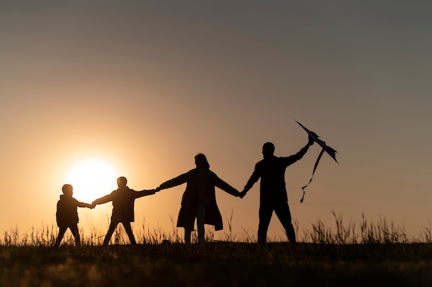 Vollbild-Familiensilhouette, die Spaß bei Sonnenuntergang hat