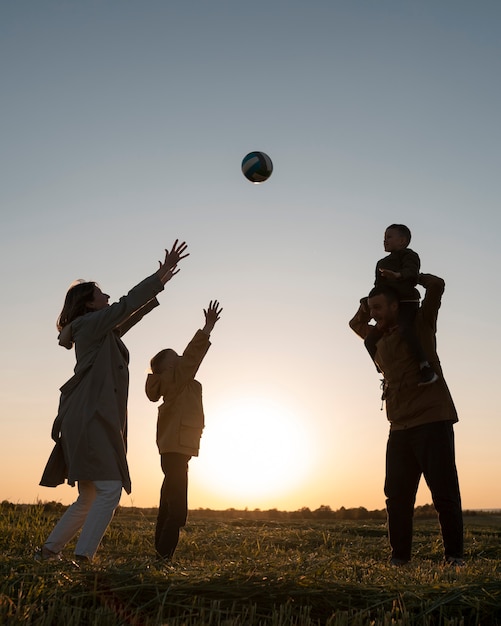 Vollbild-Familiensilhouette, die Spaß bei Sonnenuntergang hat