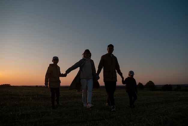 Vollbild-Familiensilhouette, die Spaß bei Sonnenuntergang hat