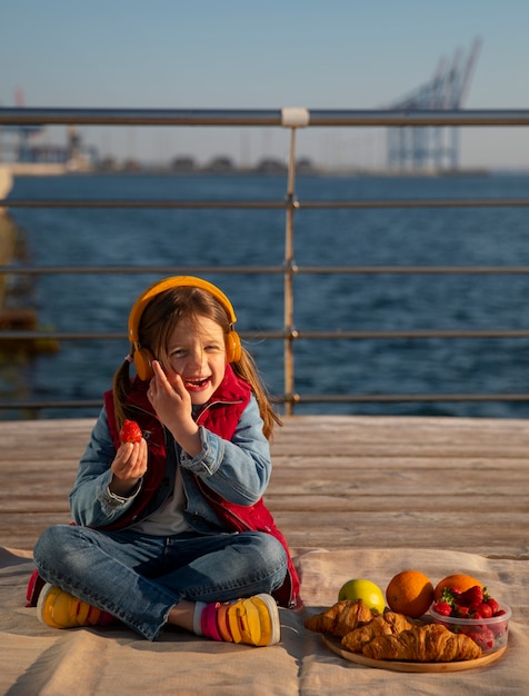 Kostenloses Foto vollbild-kind mit essen auf einem steg