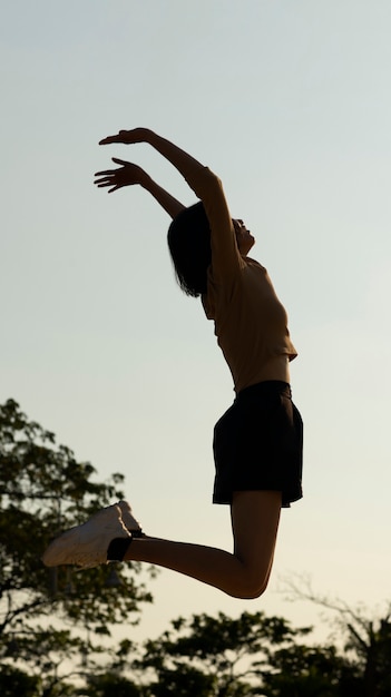 Vollbild-Silhouette einer Frau, die bei Sonnenuntergang springt