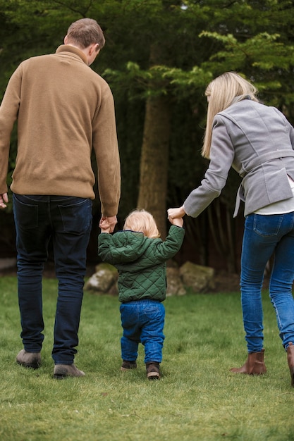 Vollbildeltern, die mit Kind im Park spazieren gehen