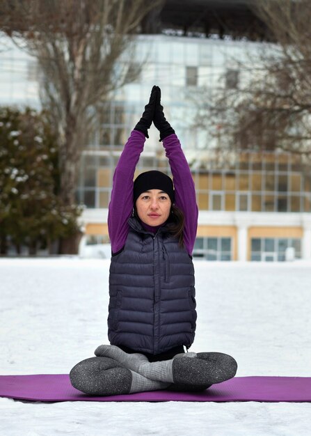 Vollbildfrau, die bei kaltem Wetter Yoga macht