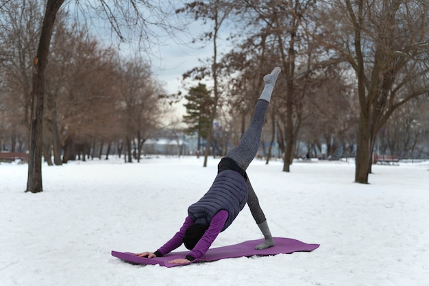 Vollbildfrau, die bei kaltem Wetter Yoga macht