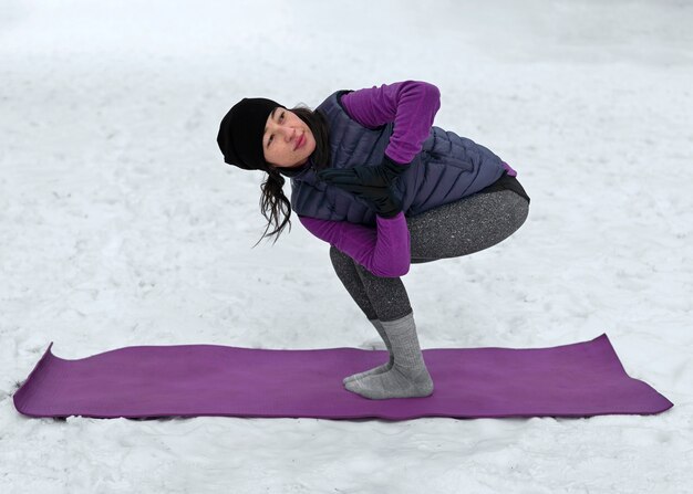 Vollbildfrau, die bei kaltem Wetter Yoga macht