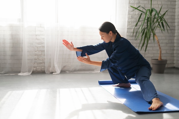 Kostenloses Foto vollbildfrau, die drinnen tai chi praktiziert