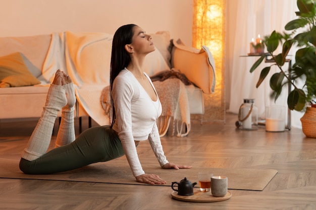 Kostenloses Foto vollbildfrau, die drinnen yoga macht
