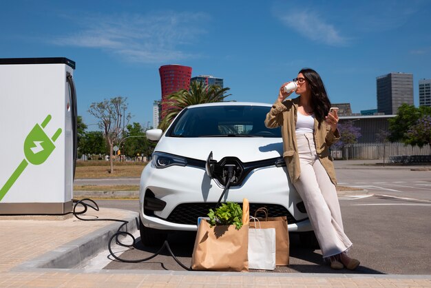 Vollbildfrau, die Kaffee in der Nähe des Autos genießt