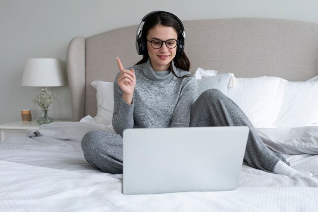 Vollbildfrau mit Laptop im Schlafzimmer