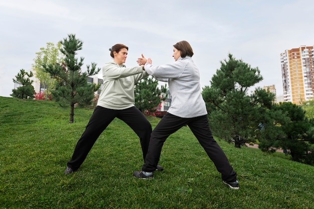 Vollbildfrauen, die draußen Tai Chi üben