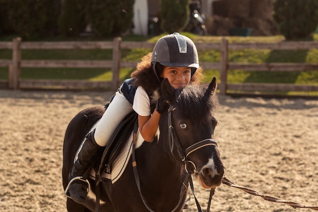 Kostenloses Foto volle aufnahme eines kindes, das reiten lernt