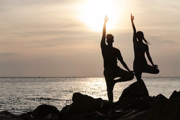 Volle Aufnahme von Menschen, die bei Sonnenuntergang Yoga machen