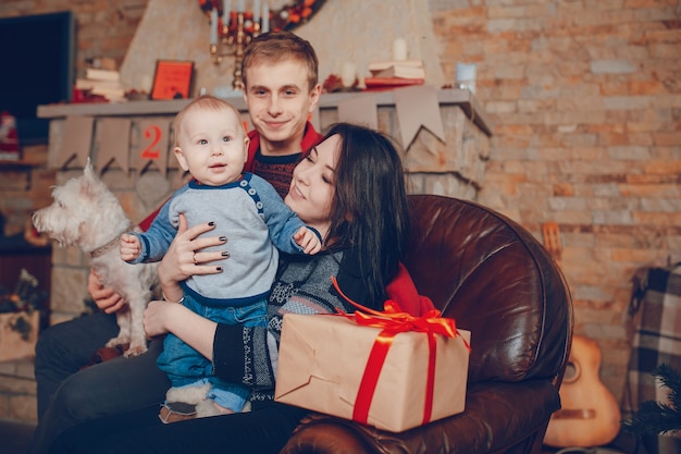 Volle Familie auf einem Sofa zu Weihnachten mit einem braunen Geschenk sitzen