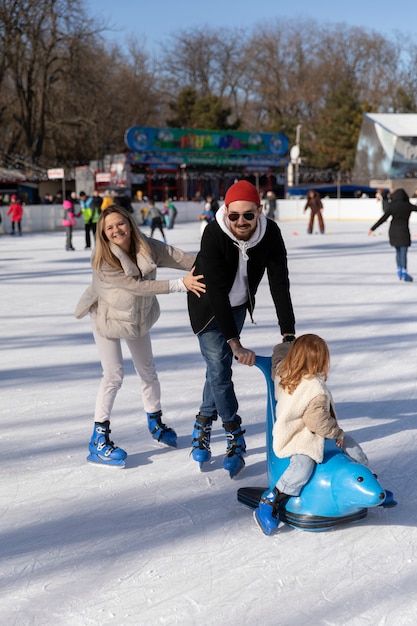 Volle glückliche familie mit kind an der eisbahn