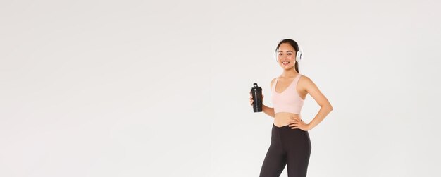 Volle Länge des schlanken und gesunden asiatischen Mädchens, das Fitness-Sportlerin im Fitnessstudio trainiert