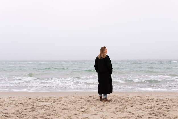 Volle Schussfrau, die am Meer sich entspannt