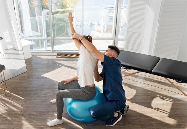 Volle Schussfrau, die auf Gymnastikball trainiert