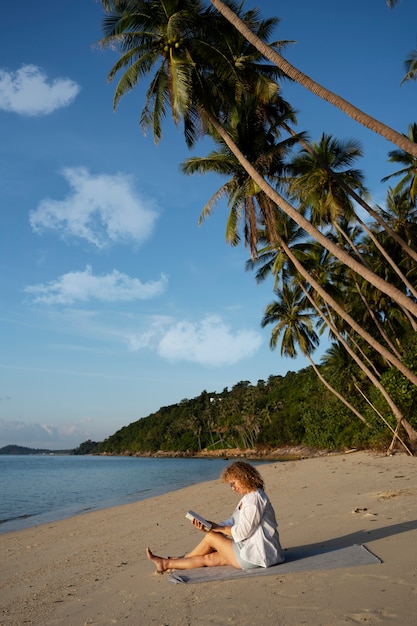 Volle Schussfrau, die auf Strand liest