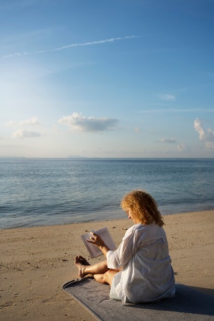 Volle Schussfrau, die auf Strand liest