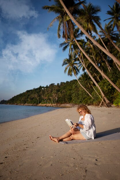 Volle Schussfrau, die auf Strand liest