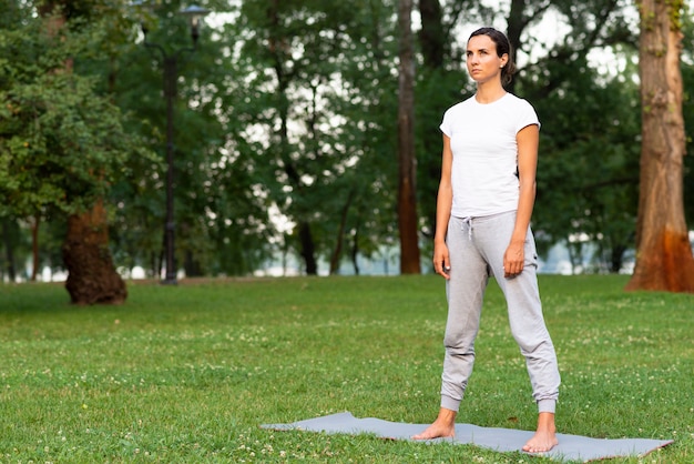 Volle Schussfrau, die auf Yogamatte steht