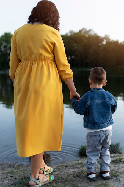 Volle Schussfrau, die die Hand des Kindes hält