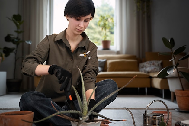 Kostenloses Foto volle schussfrau, die drinnen im garten arbeitet