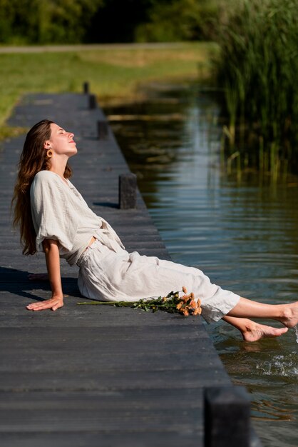 Volle Schussfrau, die durch den See sitzt