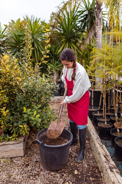 Volle schussfrau, die im großen blumentopf schaufelt