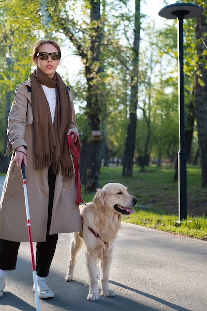 Volle Schussfrau, die mit Hund und Stock geht