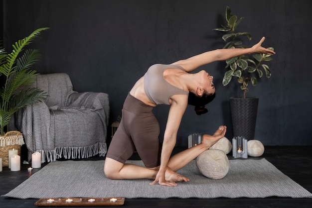 Volle Schussfrau, die zuhause Yoga tut