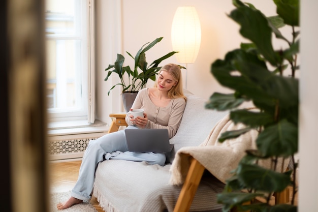 Volle Schussfrau mit Laptop auf Couch