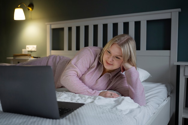 Volle Schussfrau mit Laptop im Bett