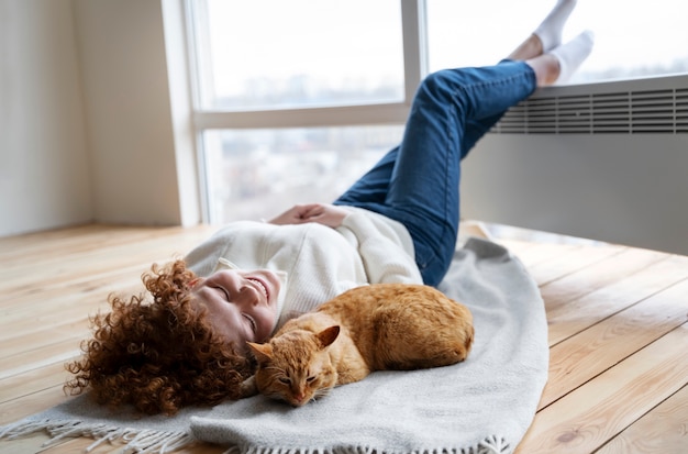 Volle Schussfrau und -katze, die auf Decke legen