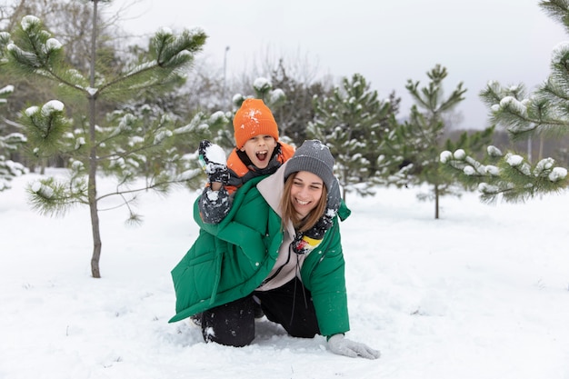 Volle Schussfrau und -kind, die mit Schnee spielen