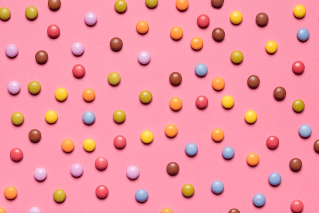 Voller Rahmen von bunten mehrfarbigen Edelstelsüßigkeiten auf rosa Hintergrund