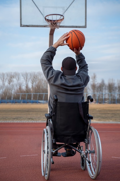 Voller Schuss behinderter Mann, der draußen Basketball spielt