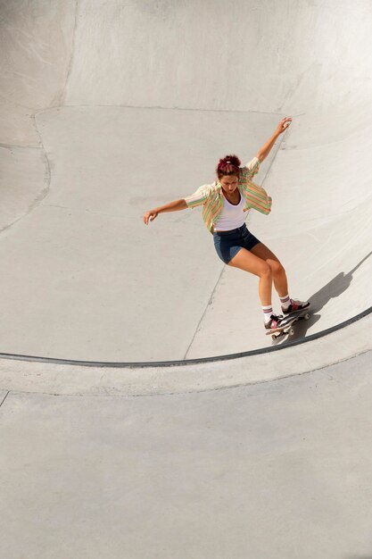 Voller Schuss coole Frau, die Spaß auf dem Skateboard hat