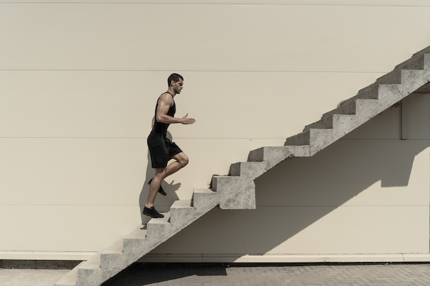 Kostenloses Foto voller schuss des gesunden athletischen mannes, der auf treppen klettert.