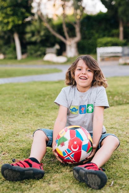 Voller Schuss des Jungen im Gras mit Fußball