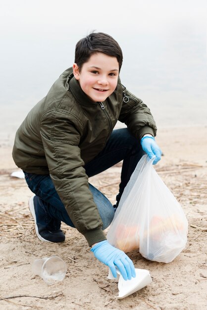 Voller Schuss des lächelnden Jungen mit Plastiktüte