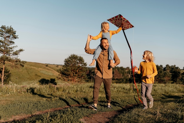 Voller schuss glückliche familie, die mit drachen spielt