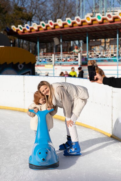 Voller Schuss glückliche Mutter mit Kind an der Eisbahn