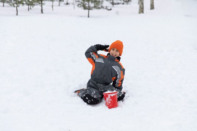 Voller Schuss glückliches Kind, das im Schnee sitzt