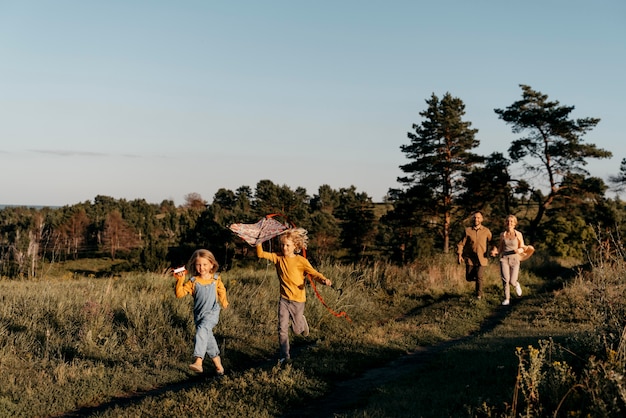 Kostenloses Foto voller schuss kinder spielen mit drachen in der natur