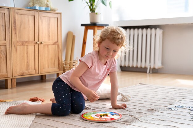 Voller Schuss kleines Mädchen, das auf dem Boden mit Puzzle spielt