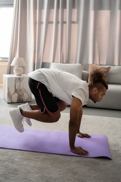 Voller Schuss Mann, der auf Yogamatte trainiert