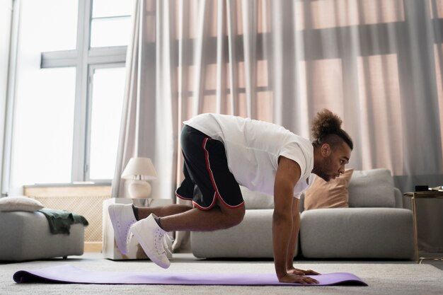 Voller Schuss Mann, der drinnen auf Yogamatte trainiert