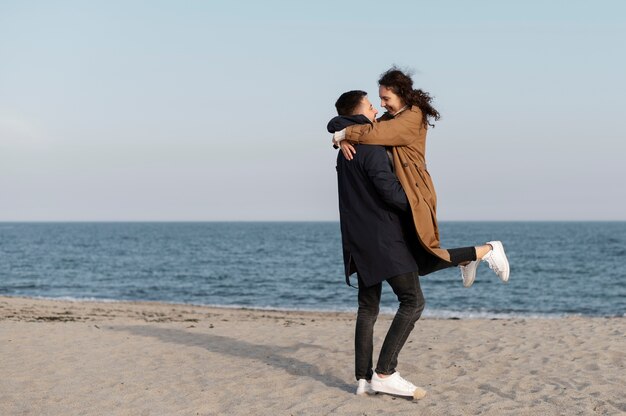 Voller Schuss Mann, der Frau am Strand hält